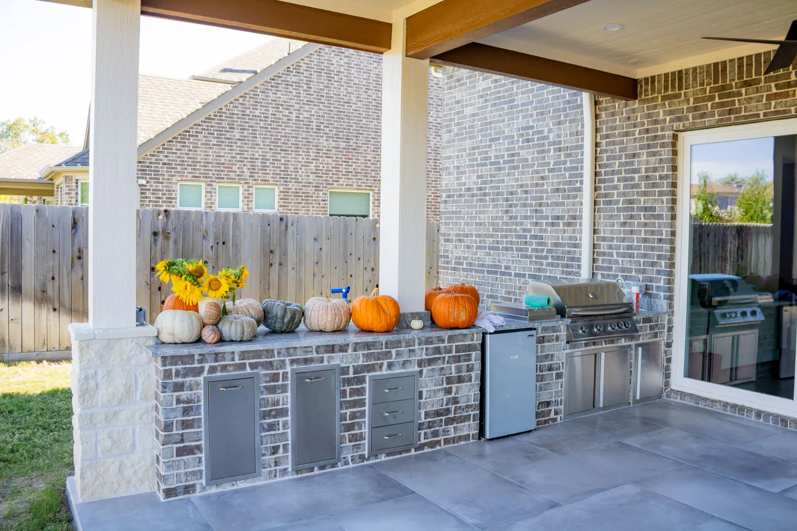 Covered outdoor kitchen with brick cabinetry and a built-in grill