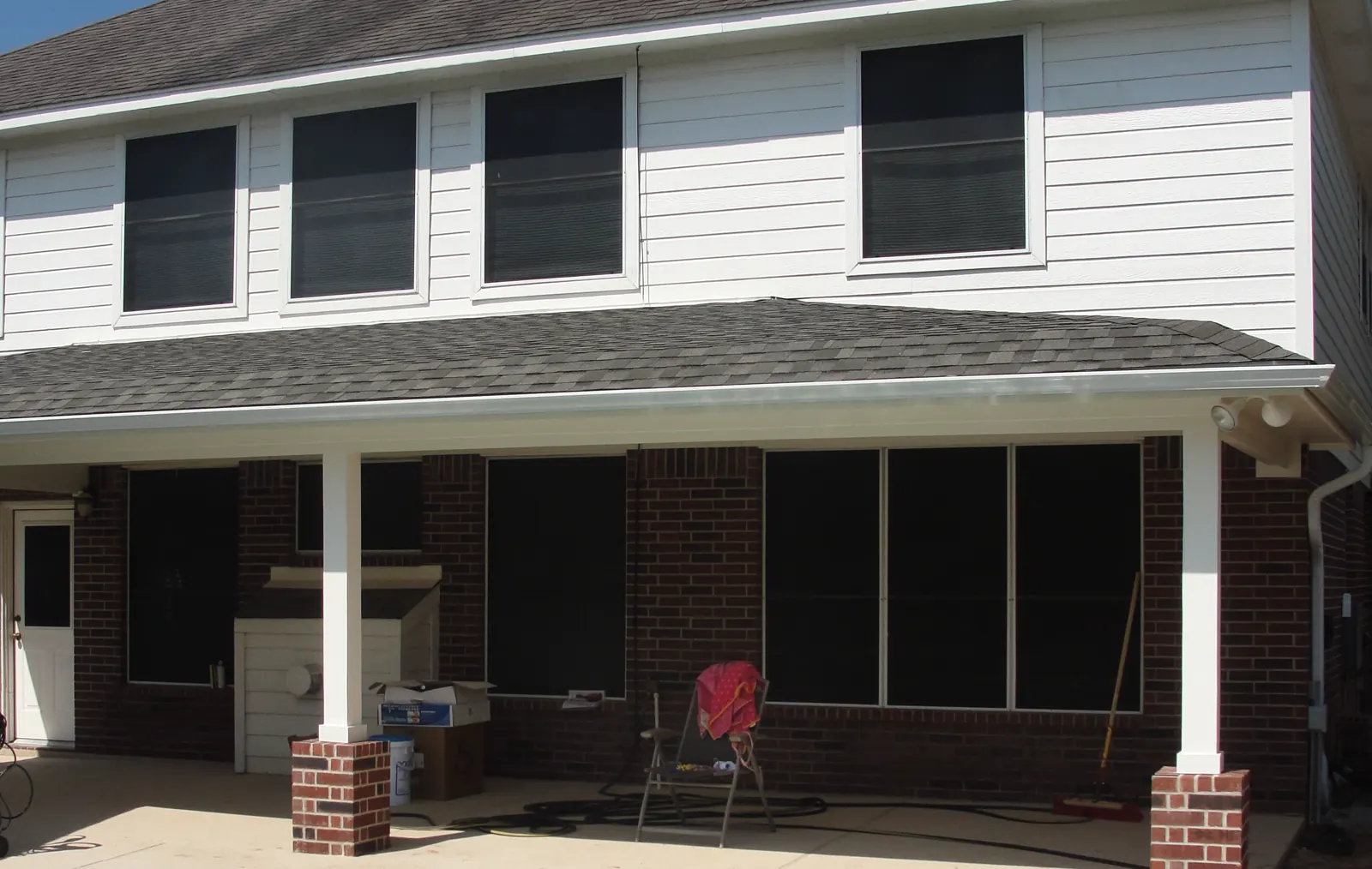 White horizontal siding above a covered patio beside a backyard pool