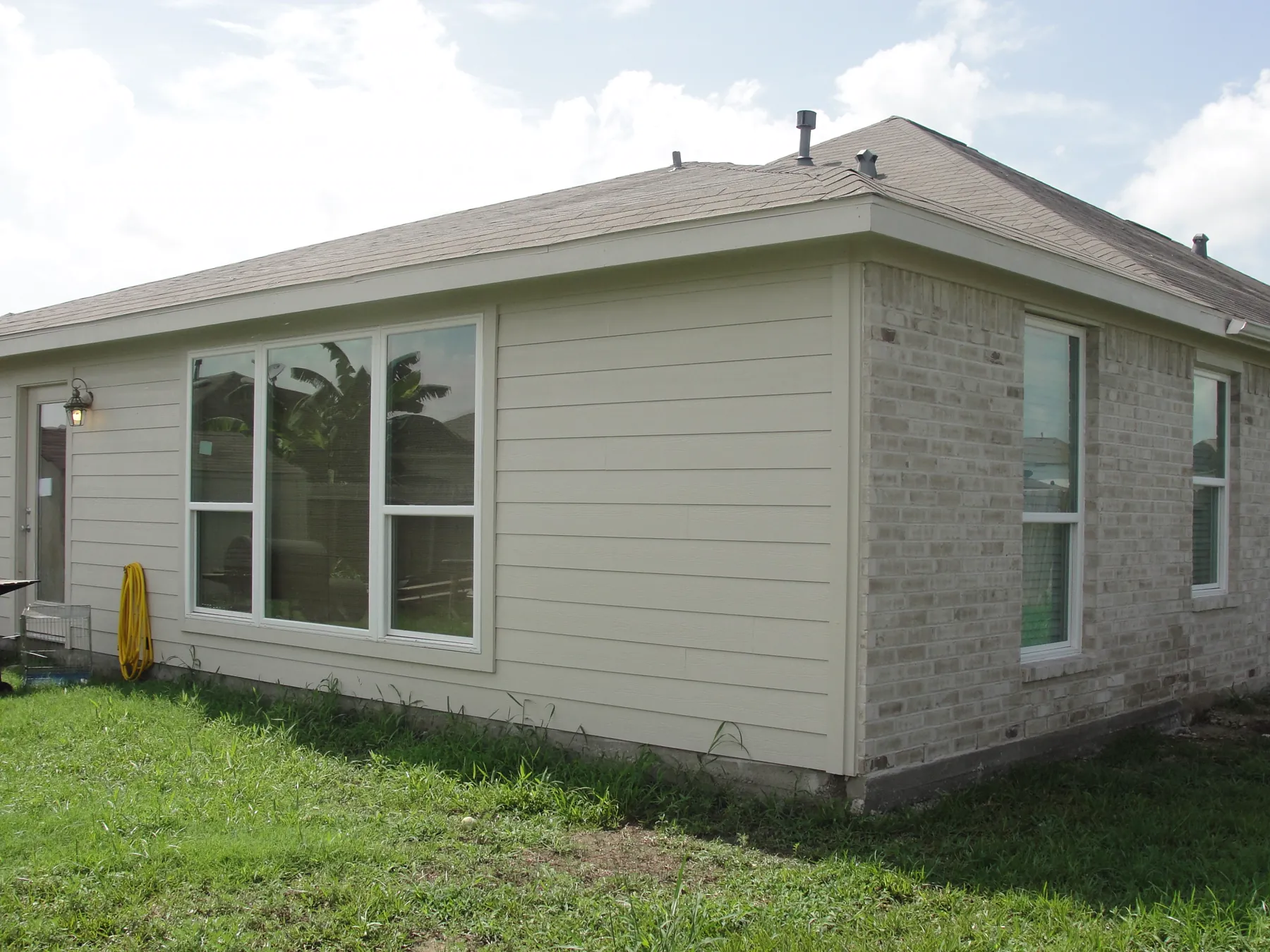 New horizontal siding and window trim beside an existing brick exterior