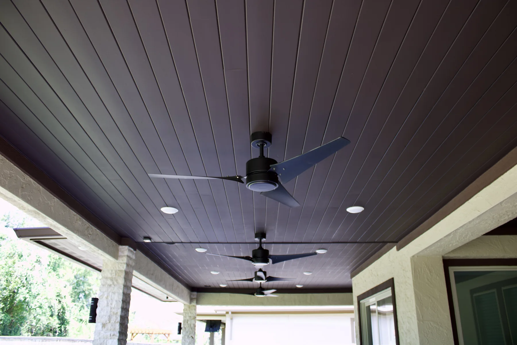 Lower covered patio with stained-wood ceiling and ceiling fan
