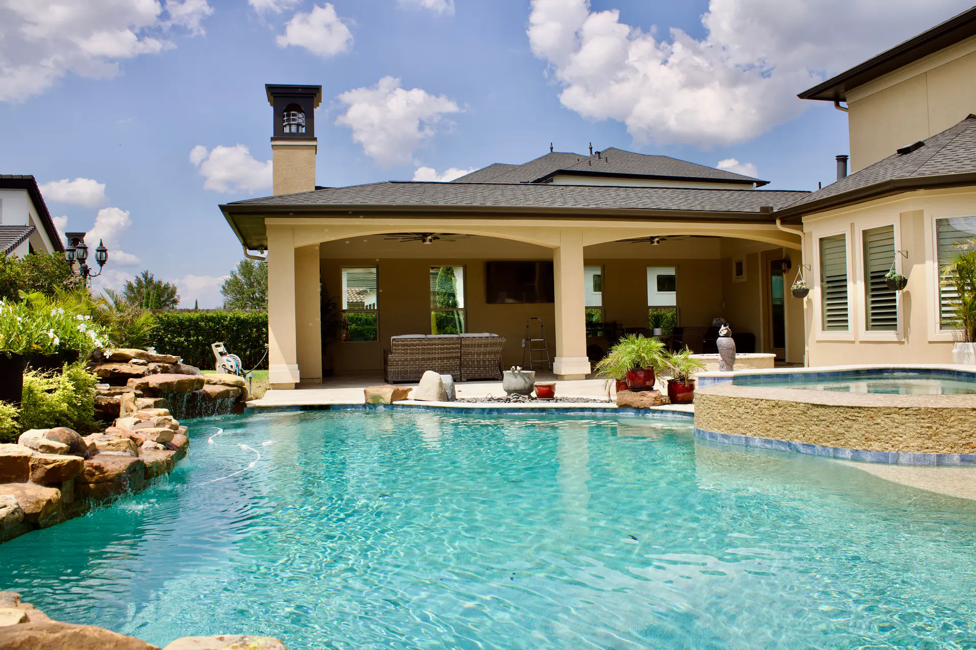 Poolside covered patio with arched openings and ceiling fans