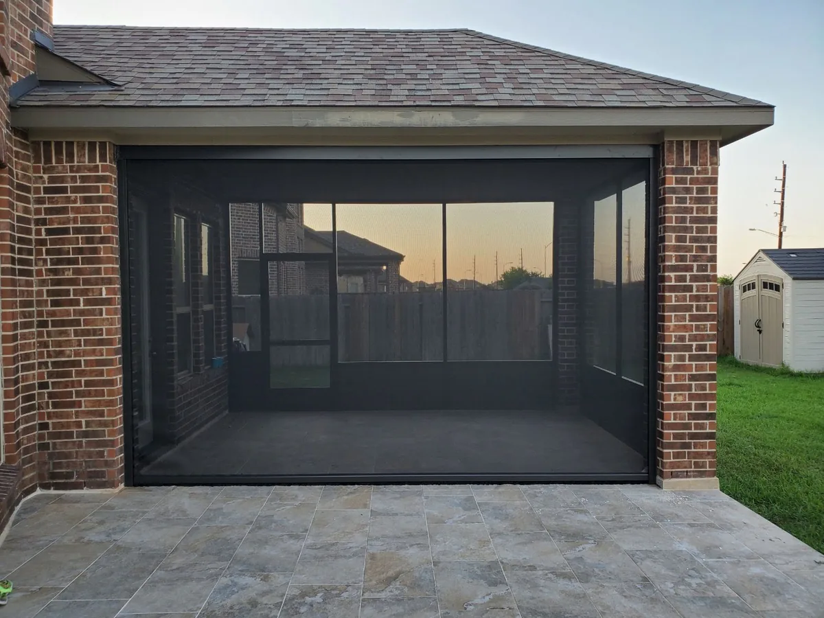 Screened patio enclosure attached to a brick home