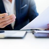 Man signing a car insurance policy the agent is holding the document